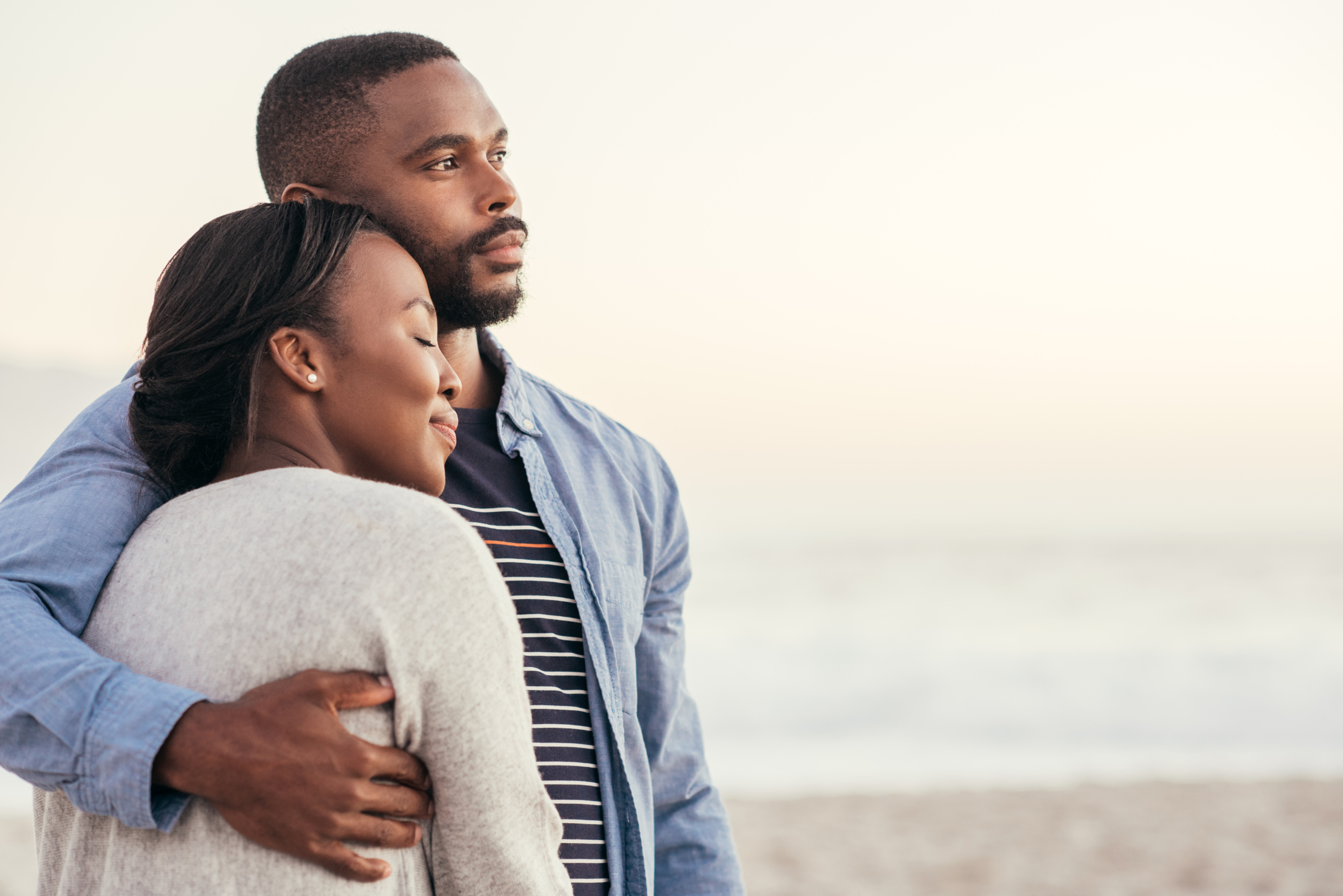 Smiling young African couple enjoying a sunset at the beach