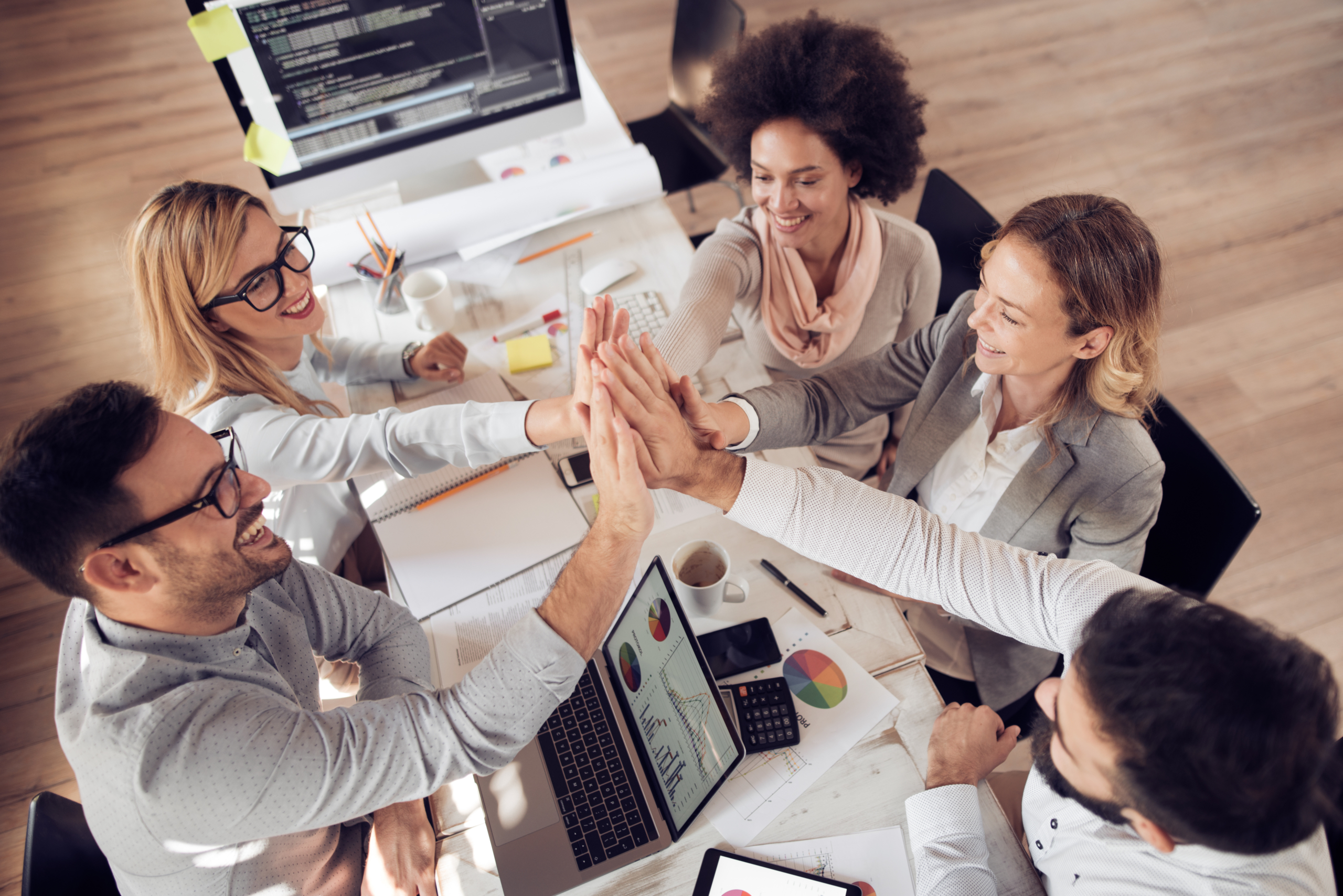 Happy business team giving high five in office